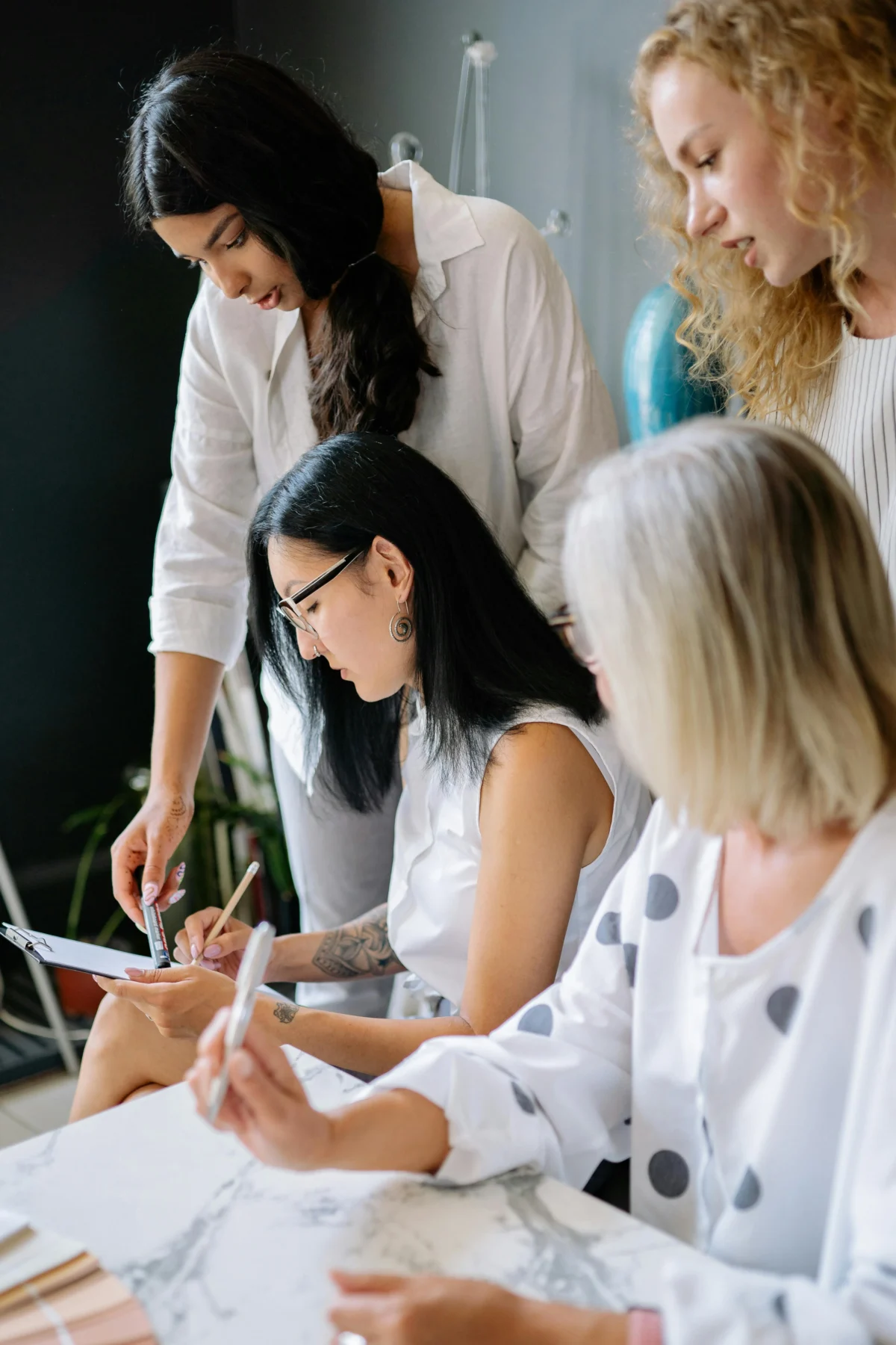 A group of diverse women brainstorming and collaborating in a modern office space.